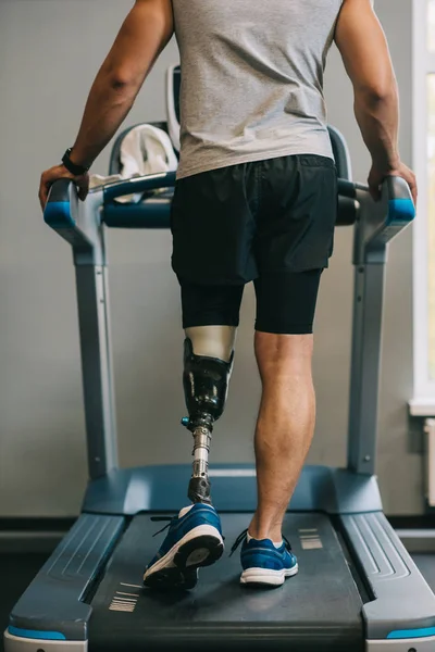 Tiro recortado de deportista con pierna artificial caminando en la cinta de correr en el gimnasio - foto de stock