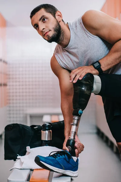 Fit young sportsman with artificial leg preparing for training at gym changing room — Stock Photo