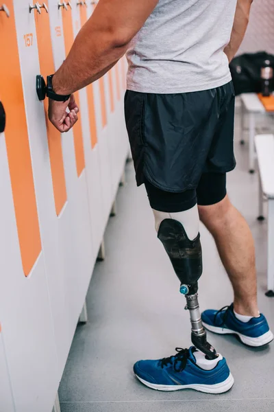 Coup recadré du sportif avec casier d'ouverture de jambe artificielle avec clé électrique sur son poignet au vestiaire de gymnase — Photo de stock