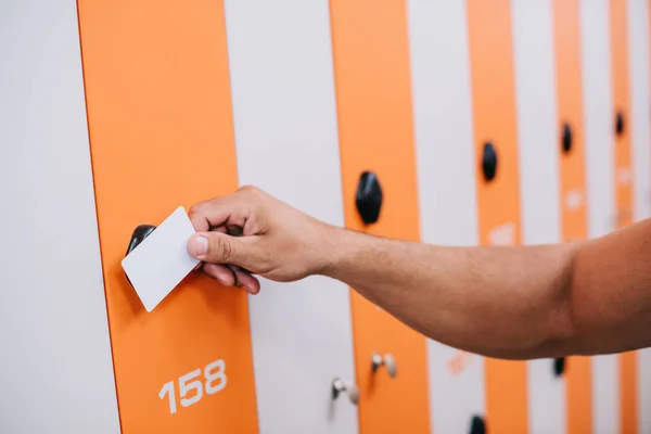 Cropped shot of sportsman magnet card to open locker at gym changing room — Stock Photo