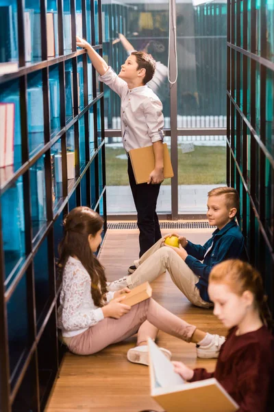 Blick aus der Vogelperspektive auf entzückende Schulkinder, die Bücher in der Bibliothek lesen — Stockfoto