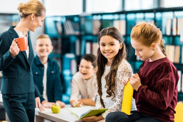 Adorabili scolari felici che leggono libri in biblioteca — Foto stock