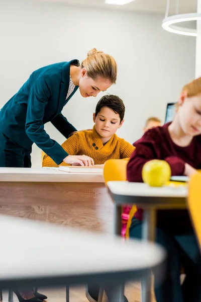 Junge Lehrerin hilft Schülern beim Lernen am Schreibtisch — Stockfoto