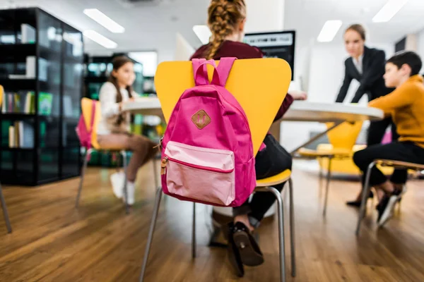 Giovane insegnante e scolari che studiano con computer desktop in biblioteca — Foto stock