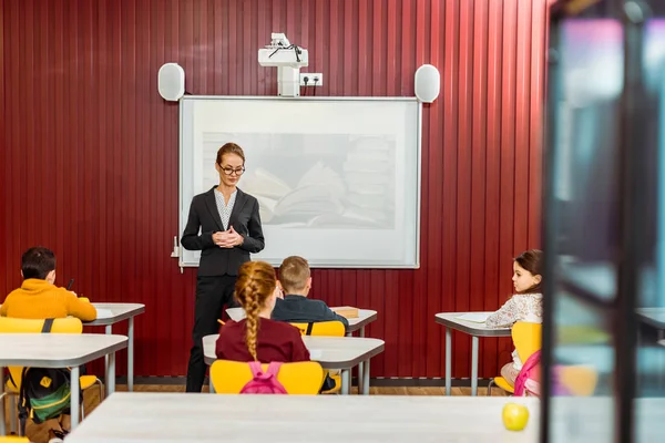 Rückansicht von Schulkindern, die am Schreibtisch sitzen und Bibliothekarin, die Präsentation macht — Stockfoto