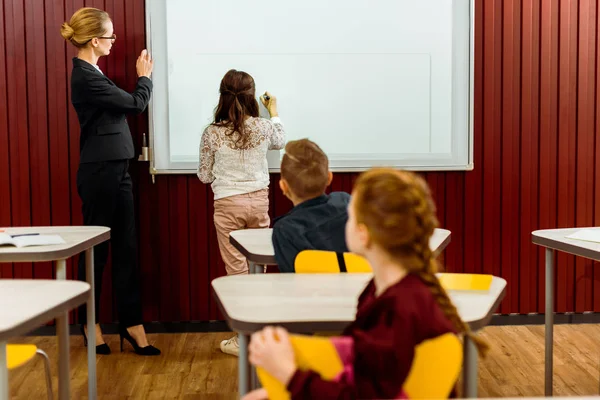 Escolares y profesores que estudian con pizarra interactiva detrás - foto de stock