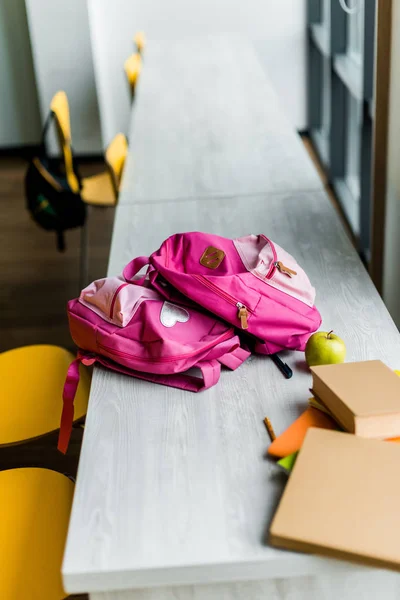 Vue grand angle des livres et sacs à dos sur les tables de la bibliothèque — Photo de stock