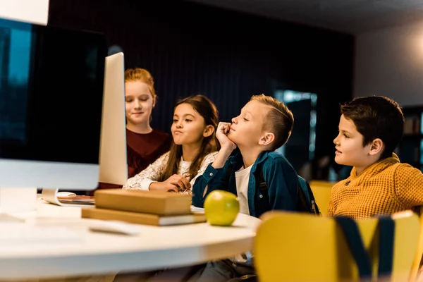 Adorable schoolchildren using desktop computer in modern library — Stock Photo