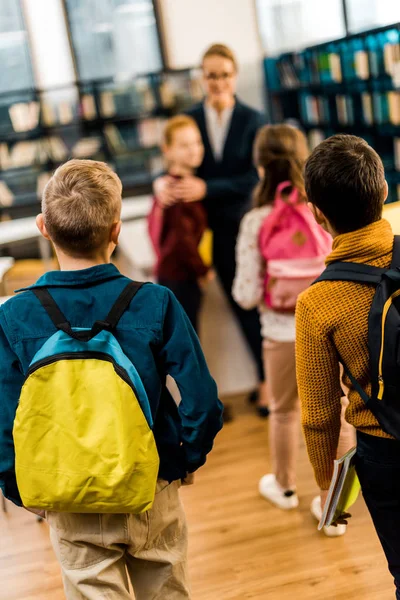 Rückansicht von Kindern mit Rucksäcken, die gemeinsam die Bibliothek besuchen — Stockfoto