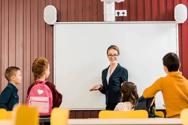 Smiling young teacher making presentation to schoolchildren — Stock Photo