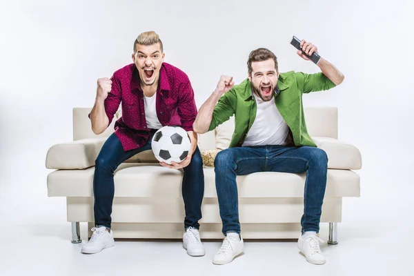 Følelsesmæssige Mandlige Venner Sidder Sofaen Med Fodbold Støtte Favorit Hold Royaltyfrie stock-billeder