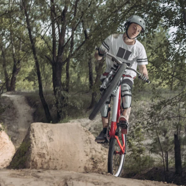 Corridore in piedi su una ruota della bicicletta nel bosco — Foto stock