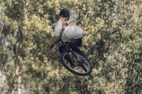 Sportif sautant avec vélo avec des arbres sur fond flou — Photo de stock