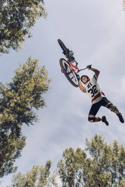 Bottom view of sportsman jumping with bike — Stock Photo