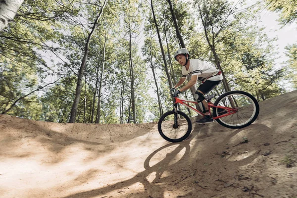 Corridore in sella alla mountain bike in pista nel bosco — Foto stock