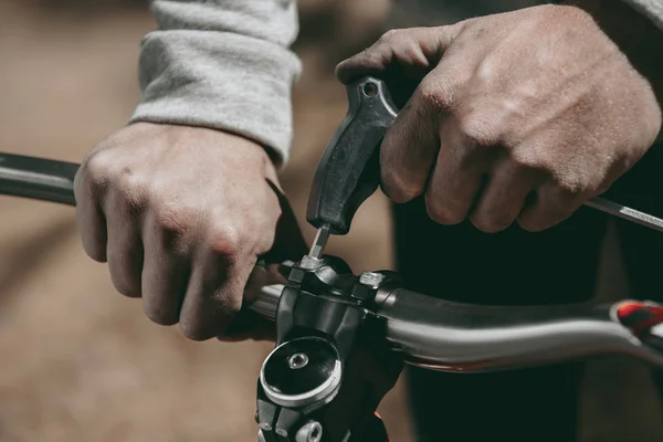 Cropped image of racer fixing bicycle on nature — Stock Photo