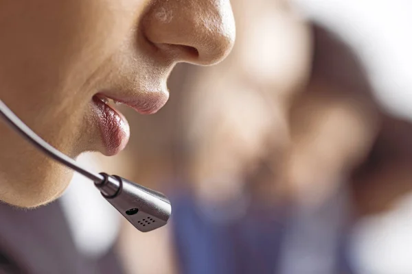 Cropped shot of call center operator in headset with blurred colleagues on background — Stock Photo
