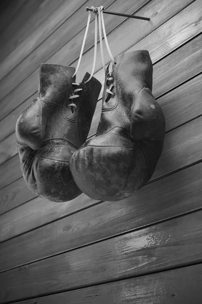 Old boxing gloves hang on nail on wooden wall with copy space for text. High resolution 3d render