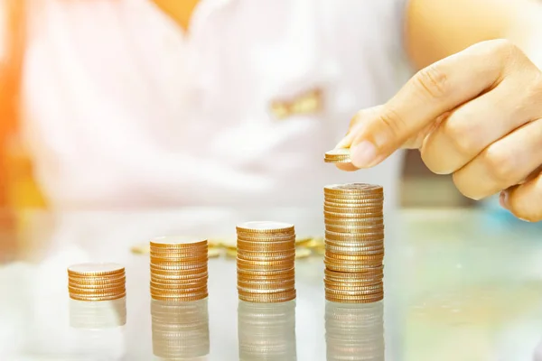 Saving money, woman stacking coins into increasing columns.