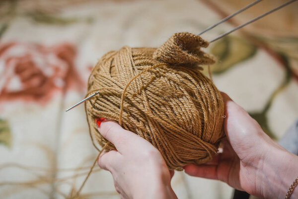 Девочка вяжет спицы. Девушка вяжет свитер спицами из шестянки ниток. Шар шерстяных нитей и спица для вязания
.