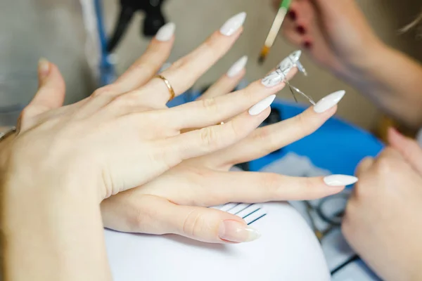 Manicure. The woman cleans and paints nails. The woman processes nails on hands a varnish. Shelak. Gel, a varnish, placing acryle on nails. Salon for manicure.