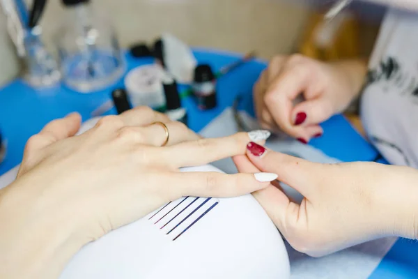 Manicure. The woman cleans and paints nails. The woman processes nails on hands a varnish. Shelak. Gel, a varnish, placing acryle on nails. Salon for manicure.