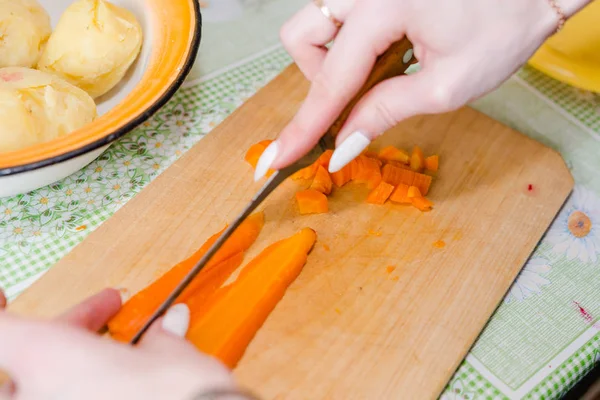 The woman cuts vegetables on salad. Cuts potatoes, beet, carrots.