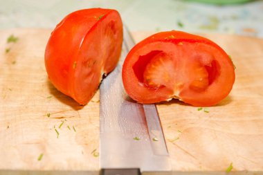 Bir domates kesmek için. Domates bir ahşap tahta üzerinde kesmek için. Salata için Tamata. Sağlıklı gıda.