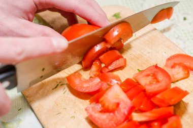 Bir domates kesmek için. Domates bir ahşap tahta üzerinde kesmek için. Salata için Tamata. Sağlıklı gıda.