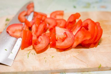Bir domates kesmek için. Domates bir ahşap tahta üzerinde kesmek için. Salata için Tamata. Sağlıklı gıda.