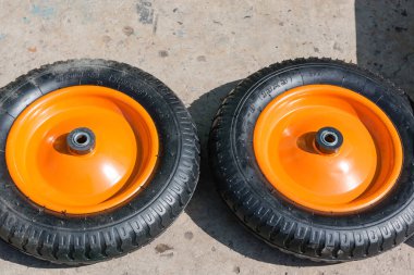 Küçük tekerlekleri üzerinden bir bahçe el arabası. Tekerlekleri asfalt üzerinde yalan. Bahçe el arabası yalan dünya üzerinde ayrı ayrı parçaları.