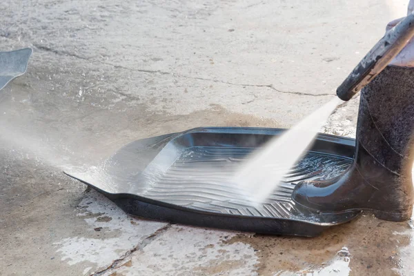 To wash automobile rubber carpets with the high-pressure apparatus. The man washes rubber carpets with water under pressure.