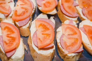 Domates ve peynirli sandviç. Domates ve peynirle ekmek dilimi bir yaprak üzerinde yatıyor. Sıcak Sandviçler hazırlanması.