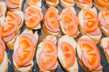 Domates ve peynirli sandviç. Domates ve peynirle ekmek dilimi bir yaprak üzerinde yatıyor. Sıcak Sandviçler hazırlanması.