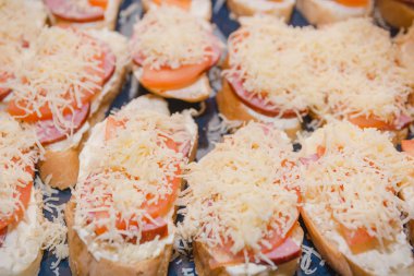 Domates ve peynirli sandviç. Domates ve peynirle ekmek dilimi bir yaprak üzerinde yatıyor. Sıcak Sandviçler hazırlanması.