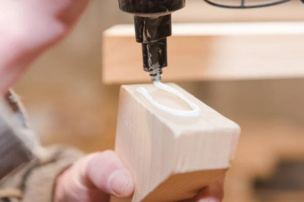 A man squeezes the glue on the wooden part. Carpentry workshop. Professional tool. Do it yourself. Glue for wooden parts. Strongly glue.
