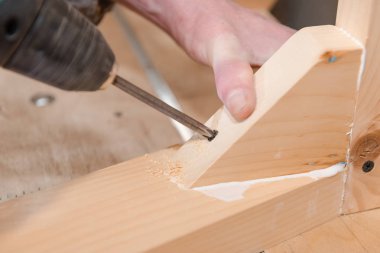 Bir adam bir vida ahşap bir masa içine dalga geçiyor. Doğrama Atölyesi. Bir tornavida ile çalışır. İş takım.