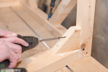 Bir adam bir vida ahşap bir masa içine dalga geçiyor. Doğrama Atölyesi. Bir tornavida ile çalışır. İş takım.