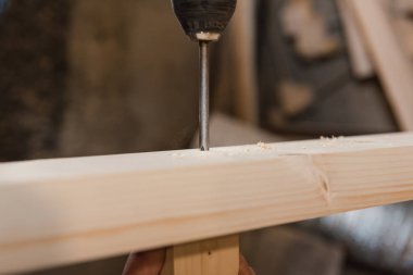 Bir adam bir vida ahşap bir masa içine dalga geçiyor. Doğrama Atölyesi. Bir tornavida ile çalışır. İş takım.