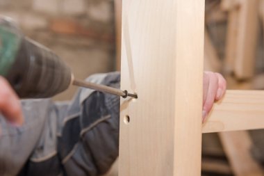 Bir adam bir vida ahşap bir masa içine dalga geçiyor. Doğrama Atölyesi. Bir tornavida ile çalışır. İş takım.