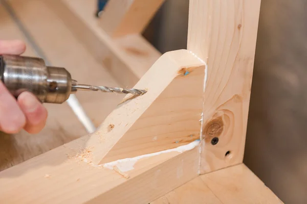 Bir adam bir vida ahşap bir masa içine dalga geçiyor. Doğrama Atölyesi. Bir tornavida ile çalışır. İş takım.