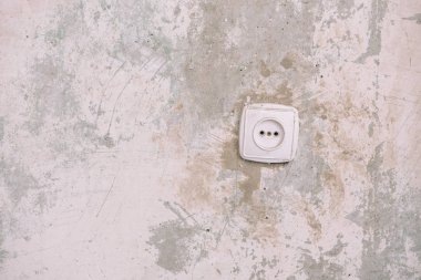 Burun duvarında soket var. Duvar kağıdı olmayan duvar. Eski duvar. Apartmanda tamirat var. Dairede duvarlar çizilmiş..