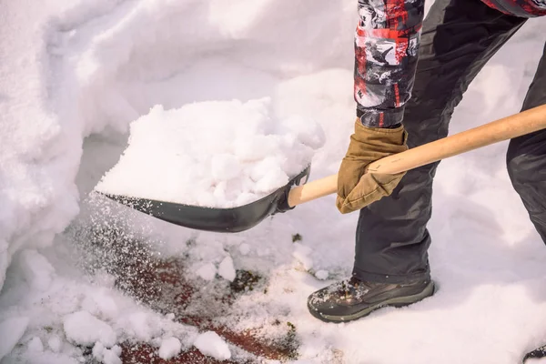 Reinig de sneeuw met een schop. De man schoppen schoppen van de sneeuw. Sneeuw schep in de hand. Schoonmaken van het gebied in de winter. — Stockfoto