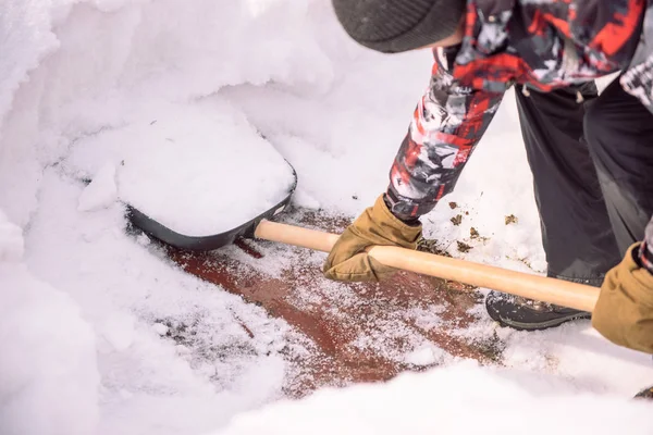 Reinig de sneeuw met een schop. De man schoppen schoppen van de sneeuw. Sneeuw schep in de hand. Schoonmaken van het gebied in de winter. — Stockfoto