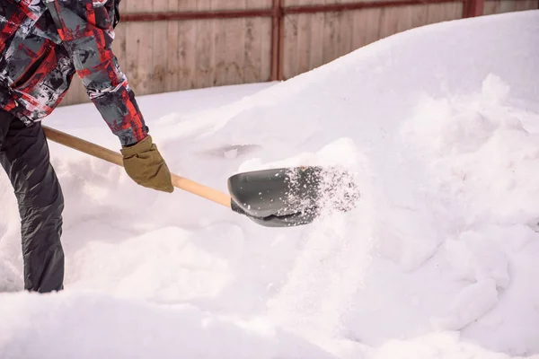 Reinig de sneeuw met een schop. De man schoppen schoppen van de sneeuw. Sneeuw schep in de hand. Schoonmaken van het gebied in de winter. — Stockfoto