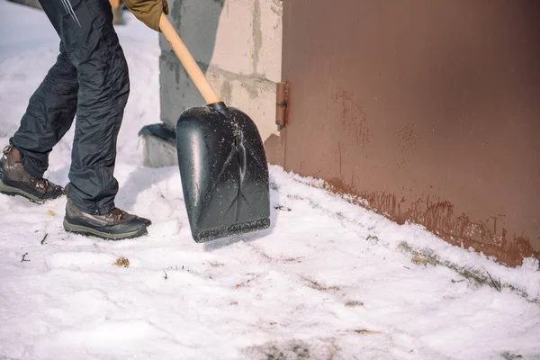 Reinig de sneeuw met een schop. De man schoppen schoppen van de sneeuw. Sneeuw schep in de hand. Schoonmaken van het gebied in de winter. — Stockfoto