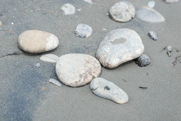 Stones on the sandy shore. Flat stones lie on the fine sand. The shore of a mountain river. Landscape in the Altai Mountains. Stones close-up.