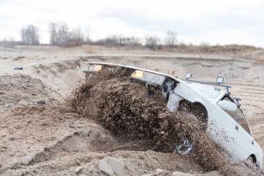 Kumsalda toplanın. Kırık araba kumsalda geziyor. Off-road sürücüsü. Araba sıçrama tahtasına atlıyor..