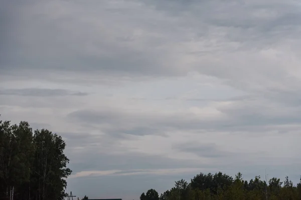 Grey sky. The sky is overhead. Clouds at sunset. The sky before the storm. Cumulus clouds. Gloomy sky. Open air.