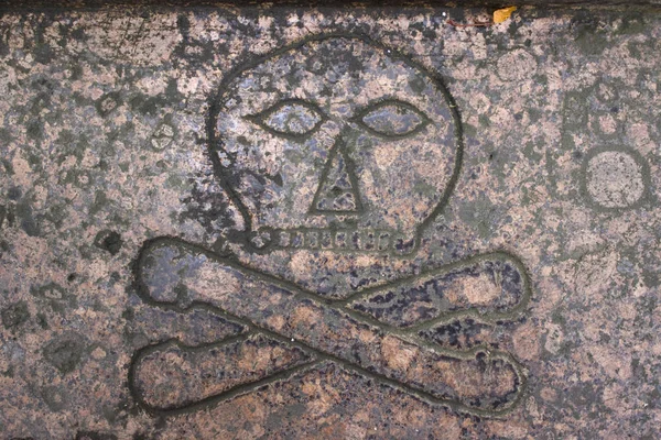 Bir taş plaka üzerinde kafatası ve çapraz kemikler